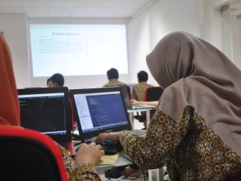 Two women in hijab at laptops in a classroom