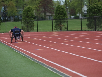 Person in wheelchair racing around track.