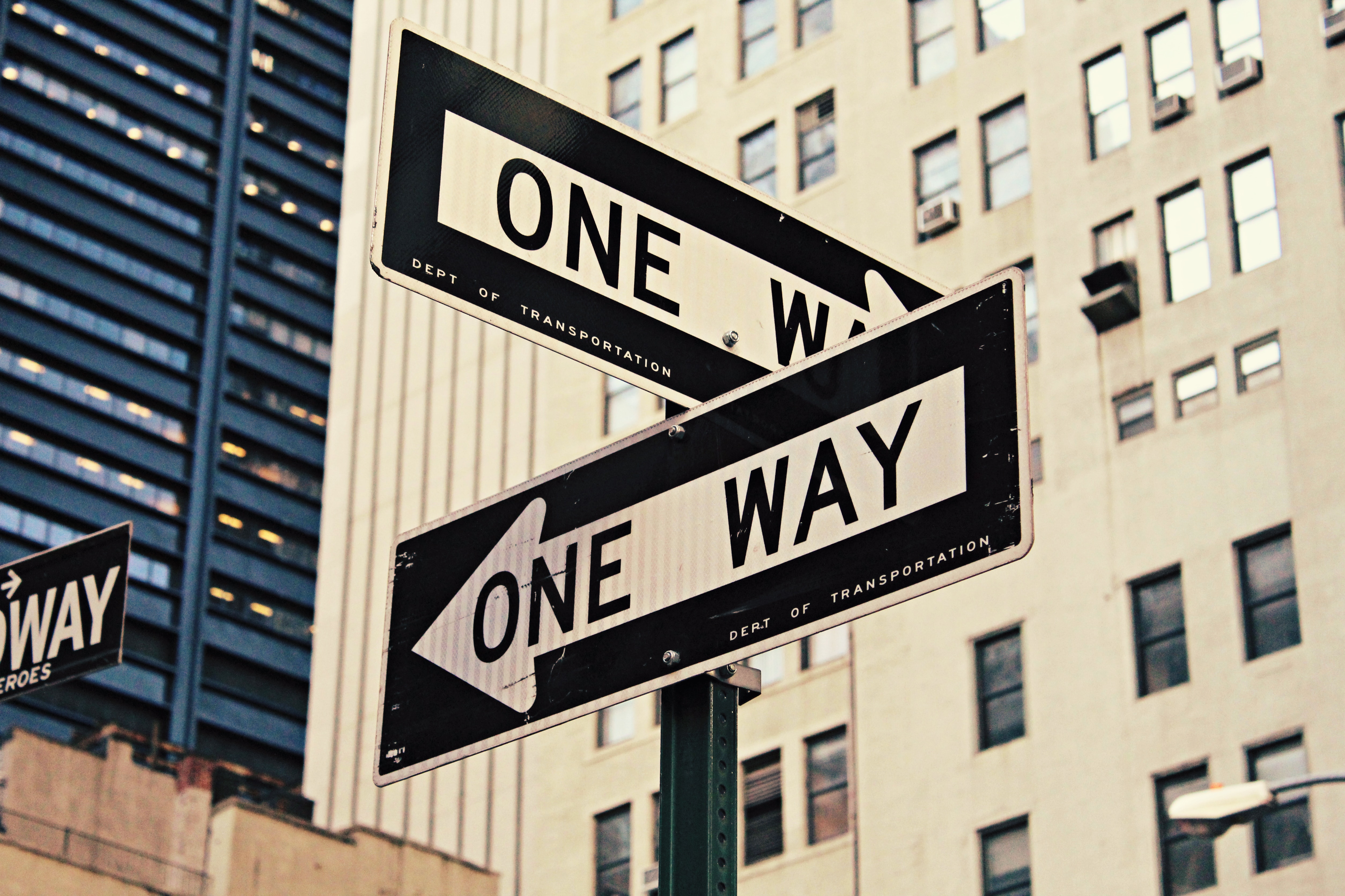 Two one way signs at a corner pointing in different directions