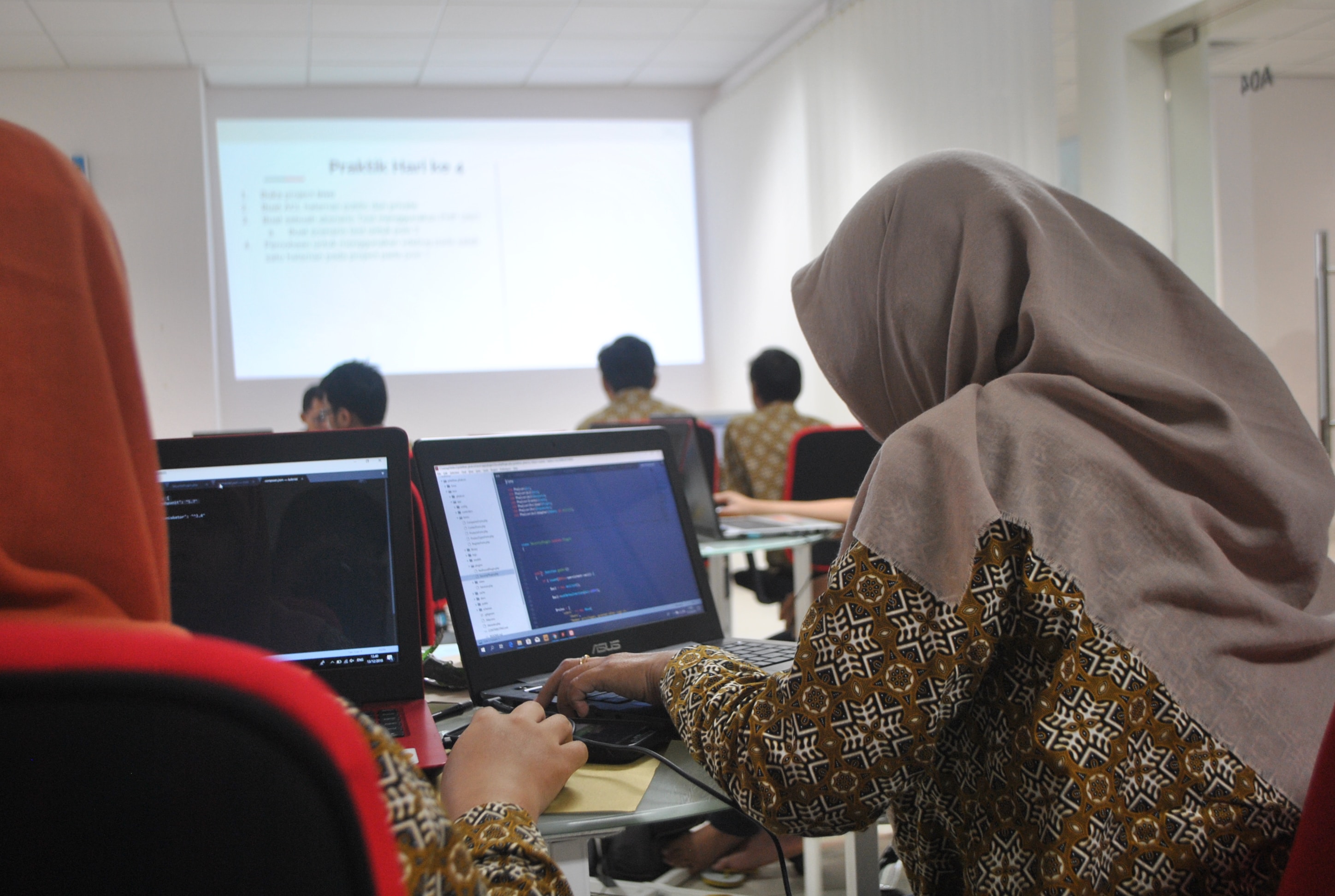 Two women in hijab at laptops in a classroom